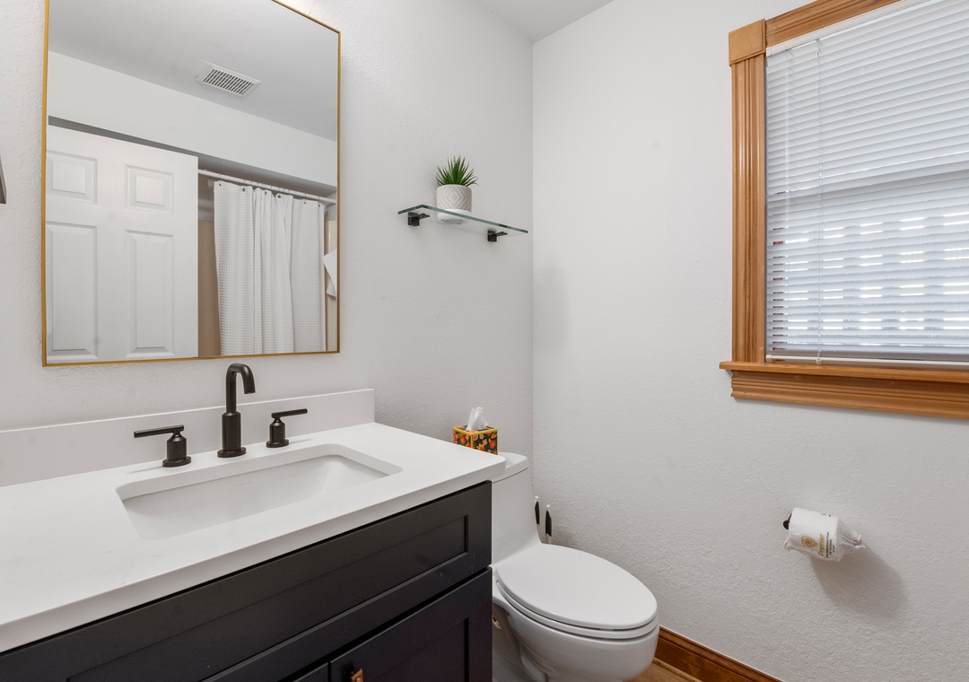 Bathroom with dark vanity and gold mirror