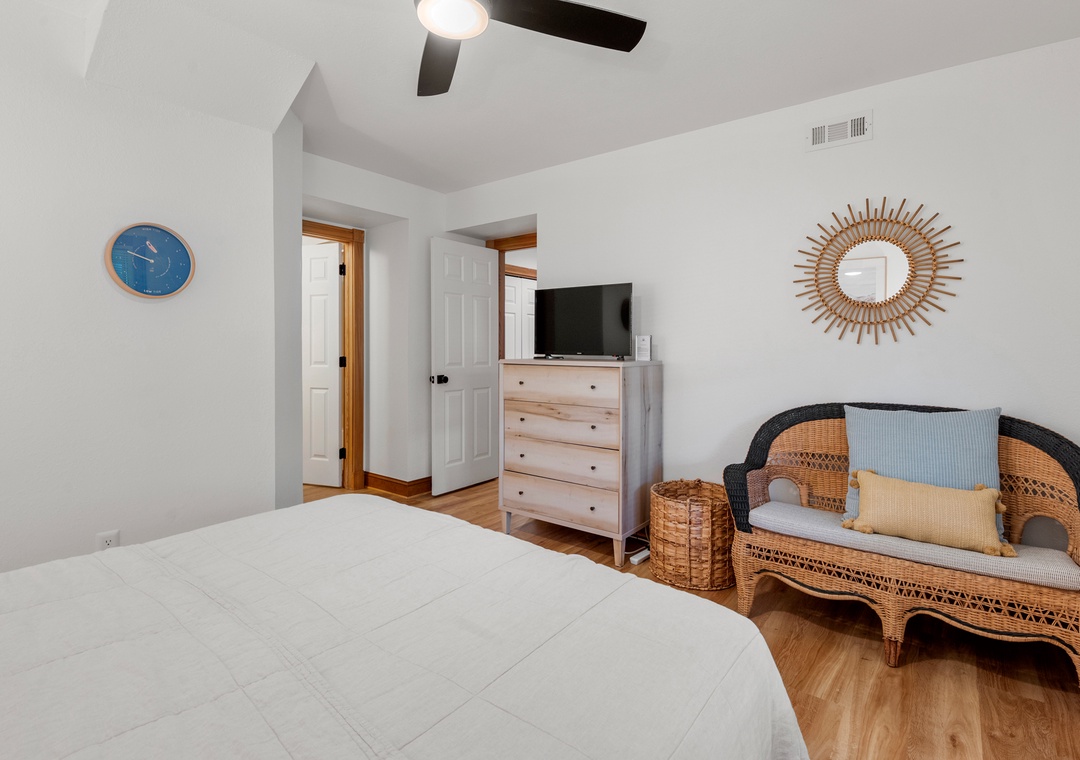 Guest bedroom with wicker settee and sunburst mirror
